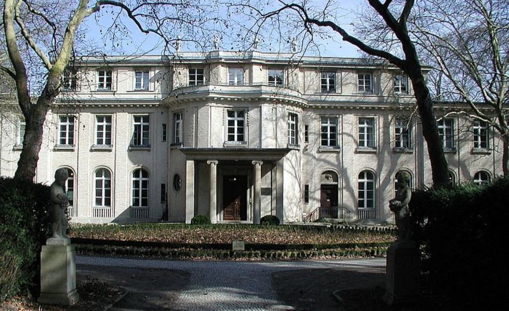 Ansicht der sonnenbeschienenen Fassade der Wannsee-Villa mit dem Haupteingang in der Mitte. 