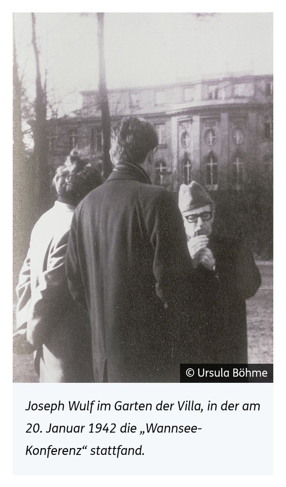 Joseph Wulf, der sich gerade eine Pfeife anzündet, steht auf der Seeseite vor der Wannsee-Villa, mit zwei weiteren Personen.