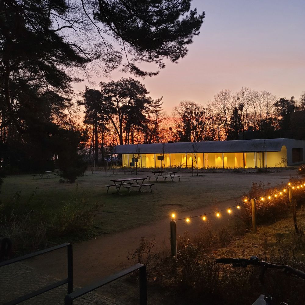 Beleuchtetes Seminarhaus der Gedenk- und Bildungsstätte Haus der Wannsee-Konferenz, Sonnenaufgang im Hintergrund
