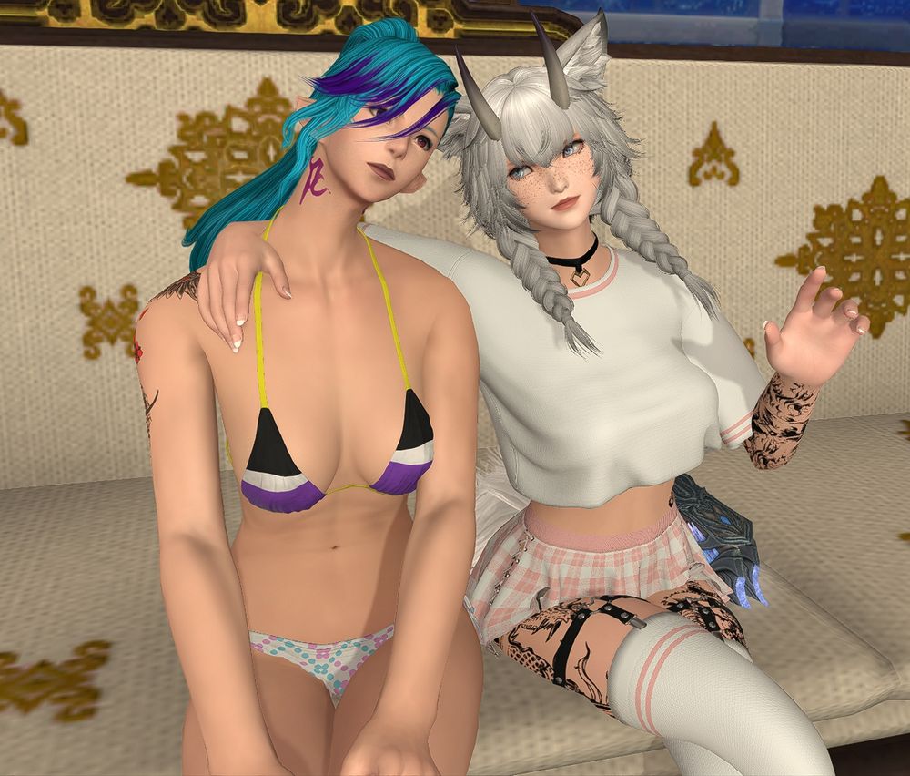 An Elezen / Elf in a bikini swimsuit (top is in non-binary colors (black, white, purple, and yellow), and the bottom is in pink, blue, and white patterns, representing the trans flag).

Sitting next to the elf is a fox girl with horns in a white top and a pink and white plaid skirt. She's wearing white and pink thigh-high socks.

The game is Final Fantasy XIV.