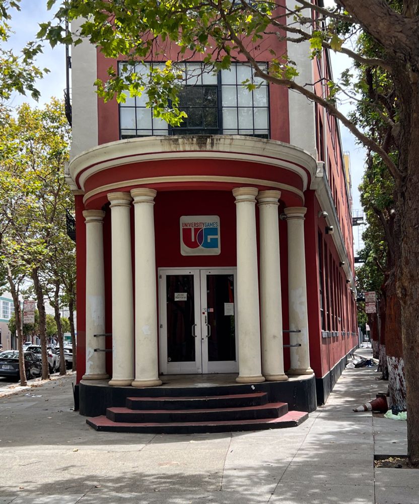 A narrow red brick building with steps and a round colonnade on its front enterest (at the narrowest corner).