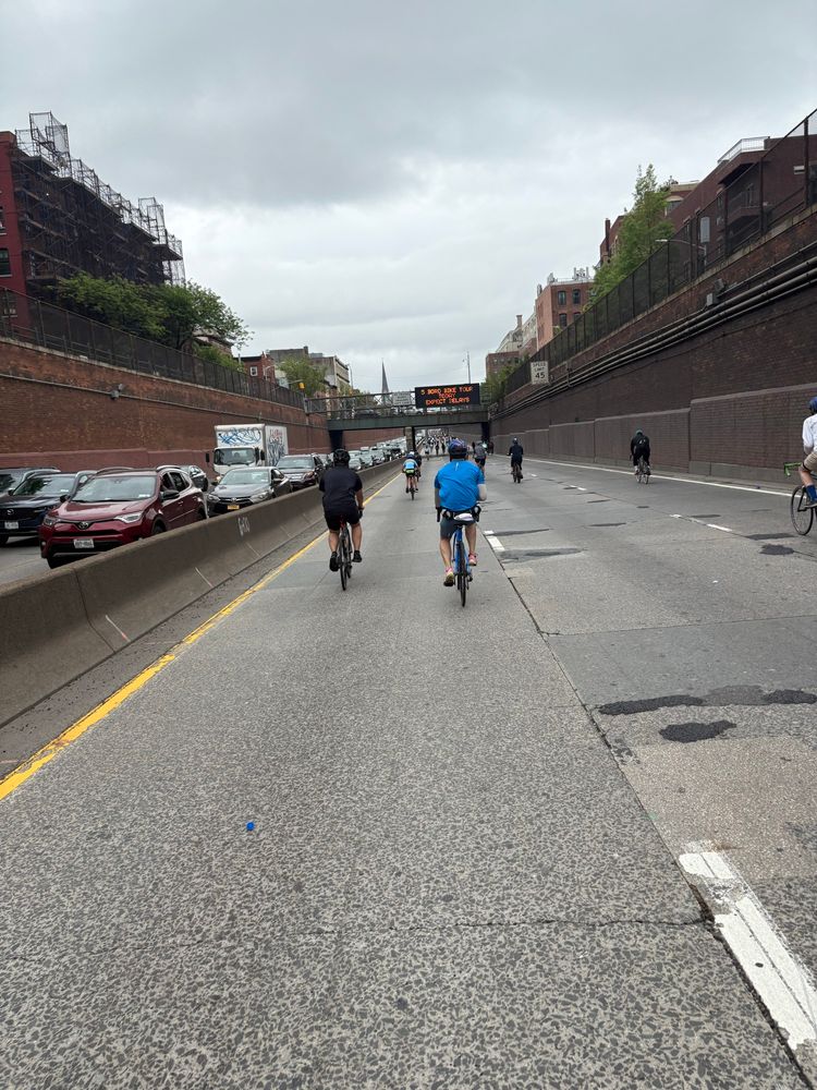 The Brooklyn-Queens Expressway during the NYC Five Boro Bike Tour. The northbound lanes are gridlocked car traffic, while the southbound lanes (where cars are banned for this event) are being enjoyed by numerous bikers in open space.