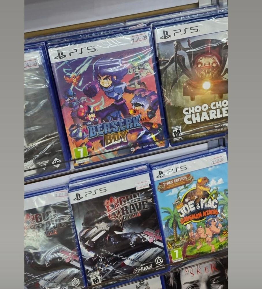 Shelf full of PS5 games, but front and center is Berserk Boy—all neon punch and Saturday morning chaos. Box art shows a fierce anime-style hero mid-leap with lightning hair, surrounded by colorful villains and fireballs.