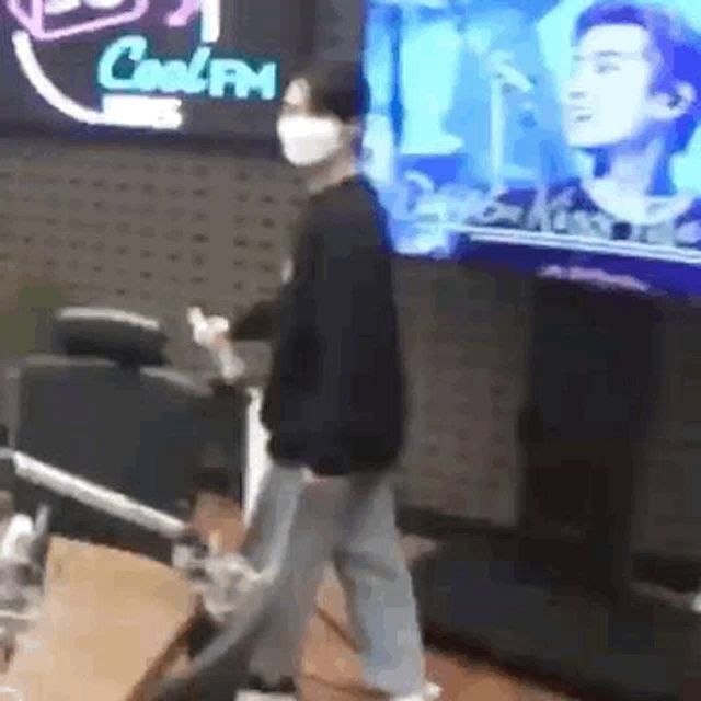 a man wearing a mask is standing in front of a television in a radio station .