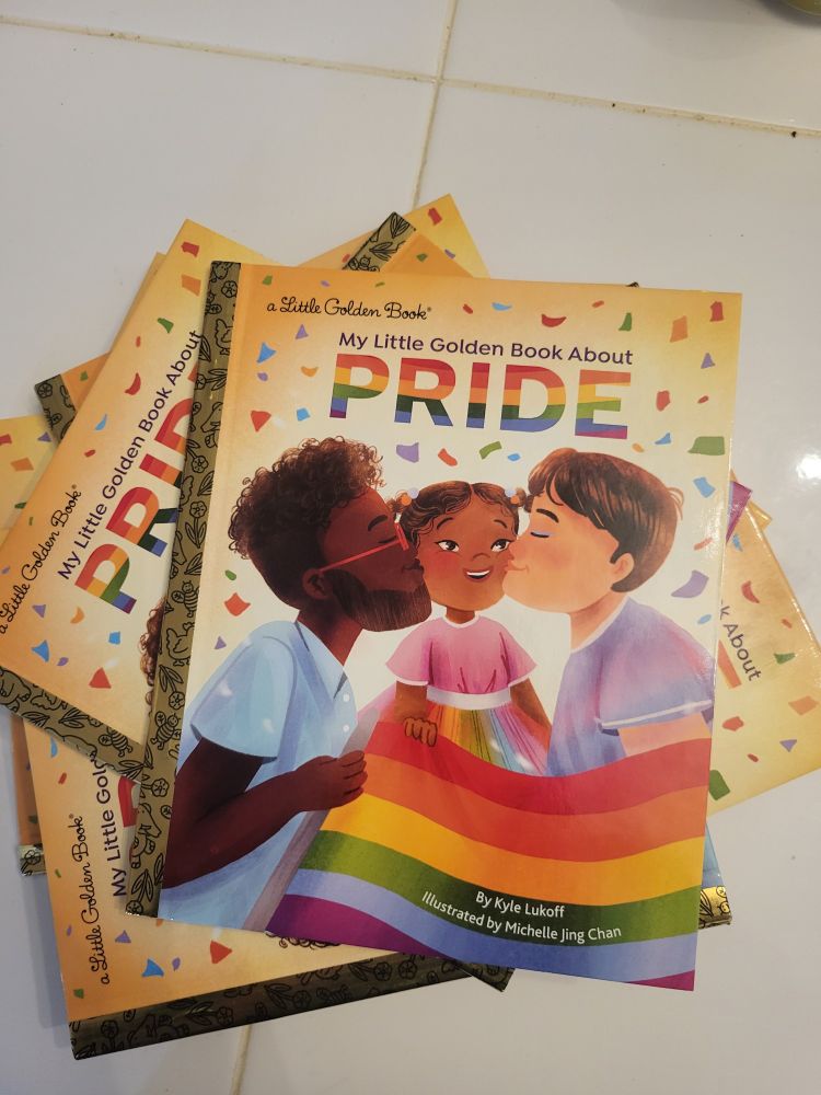 Cover of "My Little Golden Book About Pride," a multi racial queer family with a rainbow flag