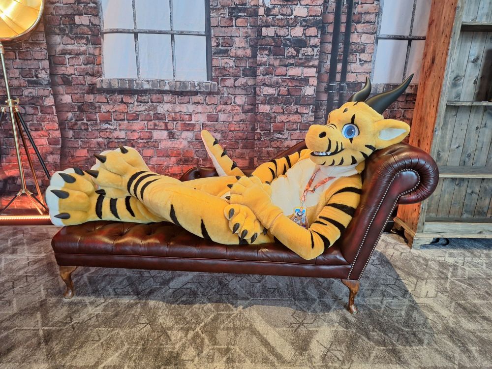 a scaly dragon lying on a recliner in a photo shoot set