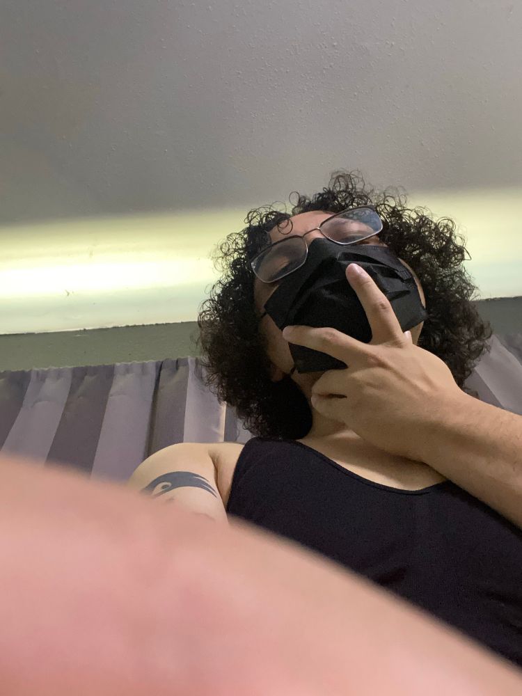 Bea holding onto you with her giant hand. Bea is wearing a black bra, black mask, and glasses. A tattoo is visible on her right arm. 