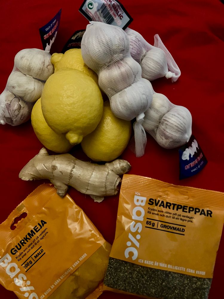 Bild på färsk vitlök, färsk ingefära, citroner, mald gurkmeja och grovmalen svartpeppar i påse från ICA Basic.