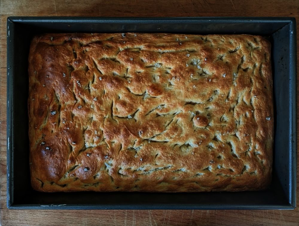A large tray of focaccia bread straight from the oven. 