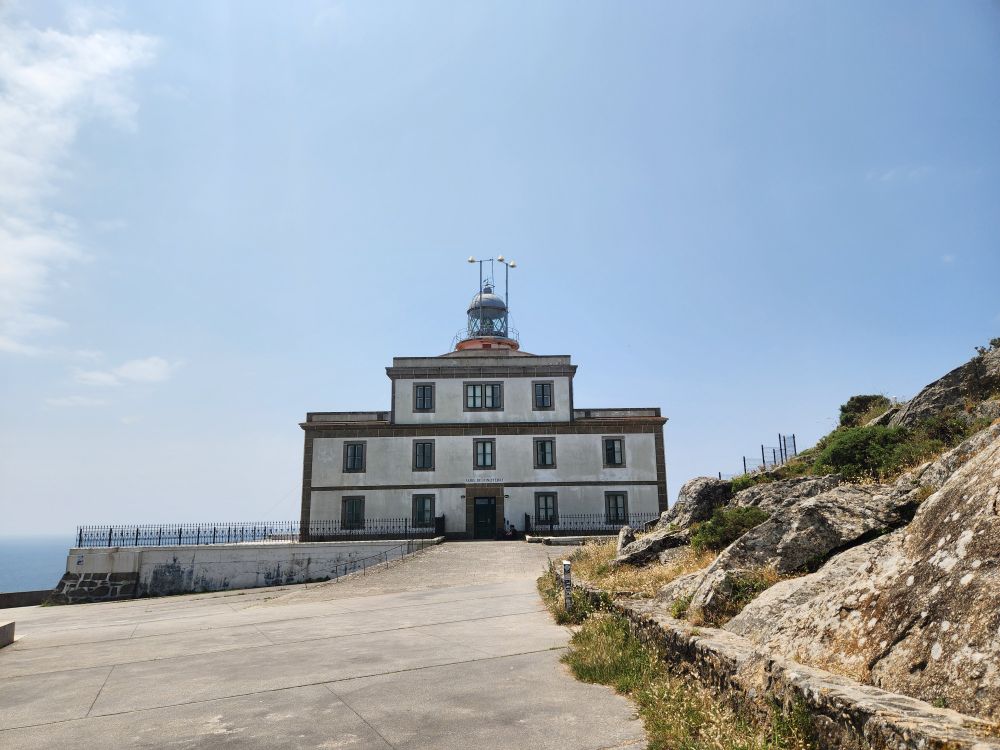A white square building with a beacon on top - the lighthouse at the end of the camino trail marks the western edge of the European world