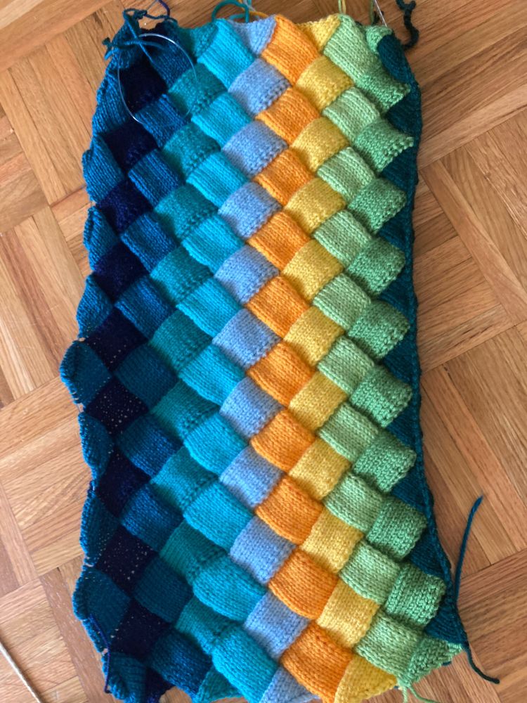 Work in progress on entrelac knitting pattern with blues, greens, and yellows.