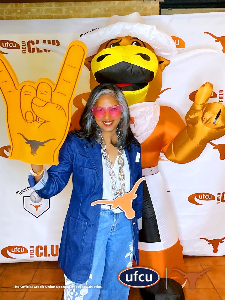Me in heart glasses wearing a giant hand signal for hook em and a large longhorn necklace 