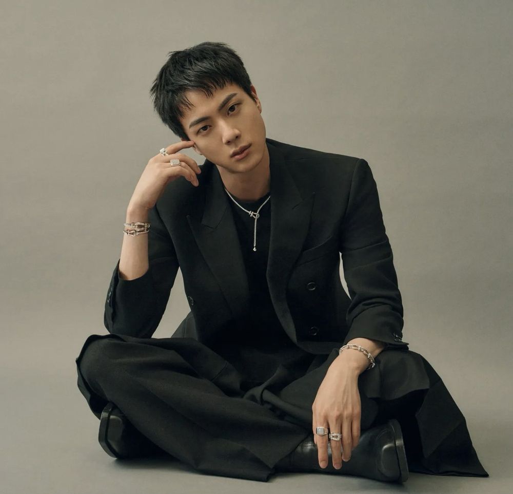 Kim Seokjin dressed in black, sitting on the floor like a handsome prince and looking at you very intensely.