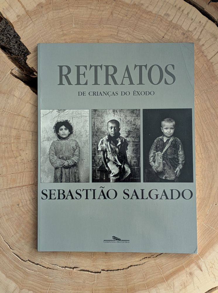 Photo of the book titled Retratos de Crianças do Êxodo by Brazilian photographer Sebastião Salgado. The book cover shows three black and white photos of migrant children.