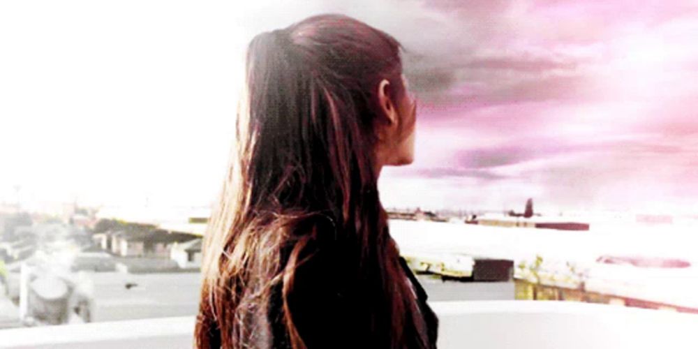 a woman with long hair in a ponytail looking out a window