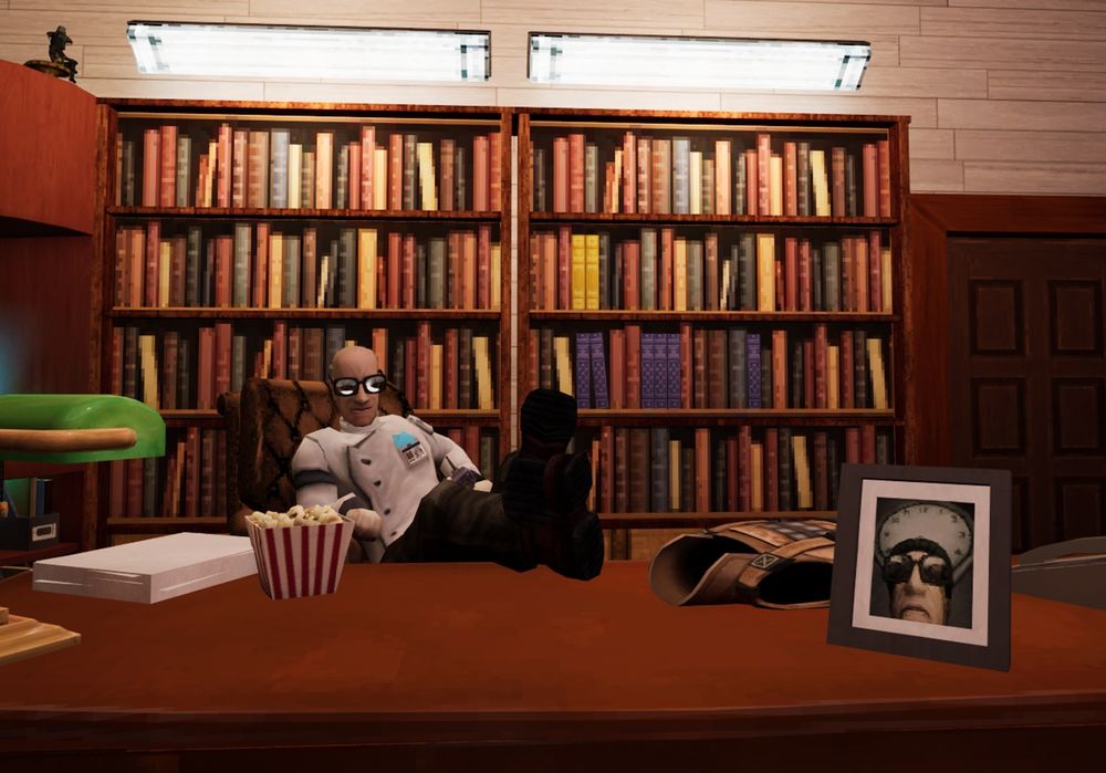 A scientist sits with their feet on a large wooden desk, holding a walkie-talkie. On the desk there is a bucket of popcorn, a stack of papers, a folded up suit of armor, a lamp, a phone and a framed photo of a scientist in front of a clock with no hands. Behind the desk are two bookshelves.