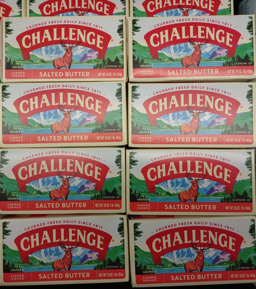 Pound boxes of Challenge brand salted butter in a refrigerated cabinet in a supermarket.
