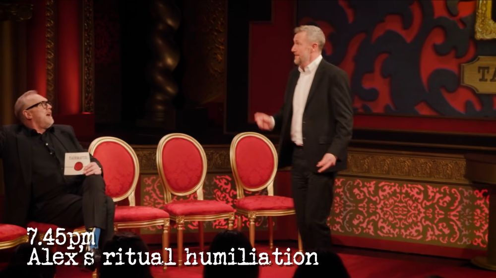A screenshot from the Taskmaster studio tour, Greg is sitting while Alex is dancing, captioned 7.45pm
Alex's ritual humiliation