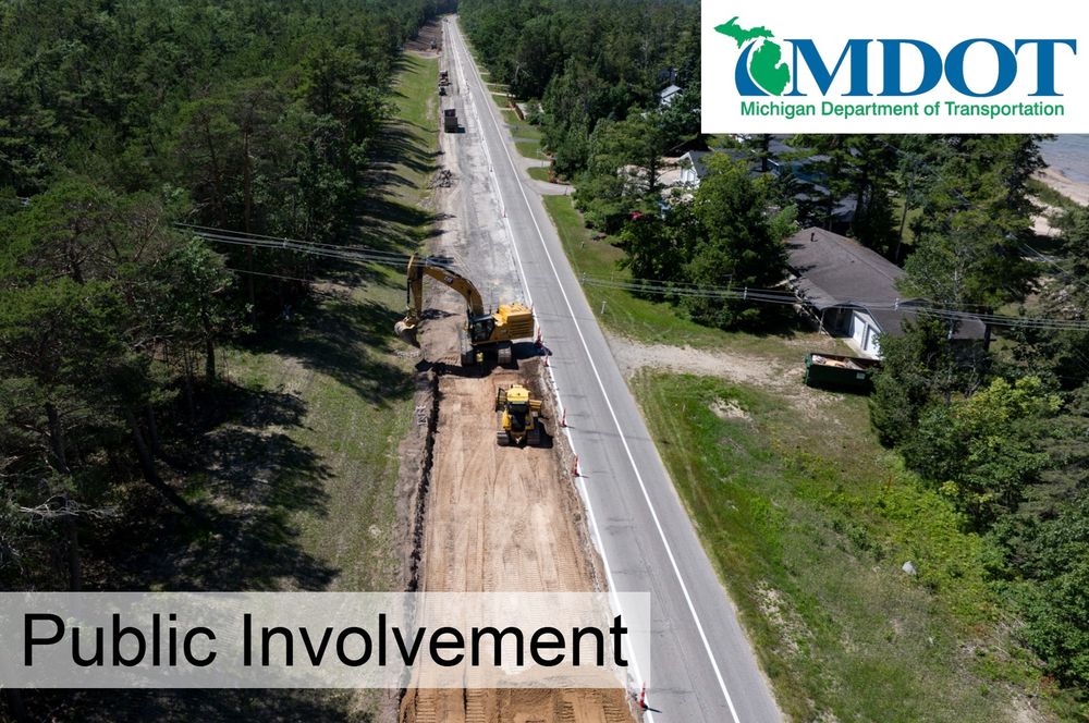 A backhoe removes old road surfacing in a rural area.