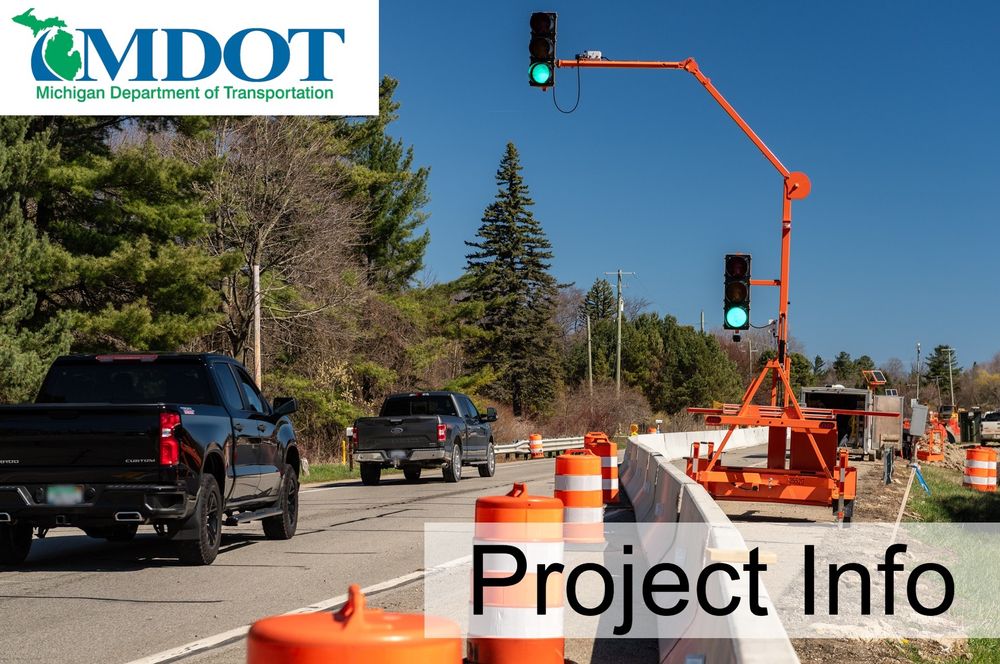 Trucks driving past traffic cones and a traffic light due to roadwork. 
