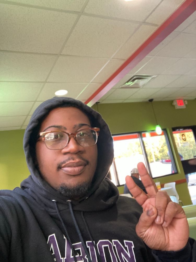 Me, taking a selfie, inna hoodie at a coffee shop, throwing up a peace sign 
