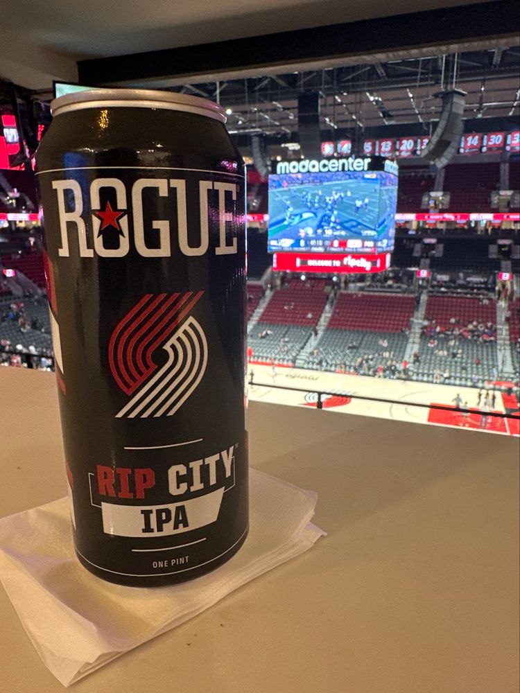 Can of Rogue beer RIP CITY IPA against a MODA Center basketball court background.