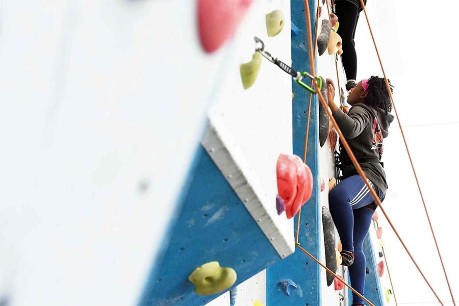 A photograph of a person climbing an indoor climbing wall. 
