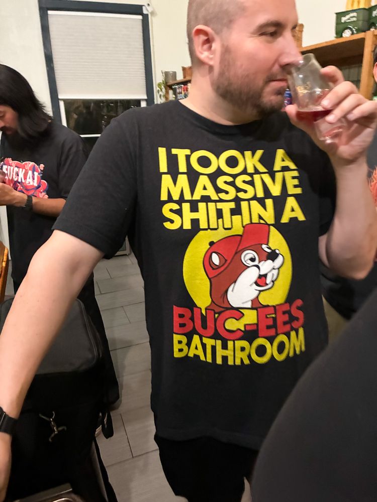 Person wearing shirt proclaiming he took a massive shit at Buc-ee’s as he drinks from a snifter