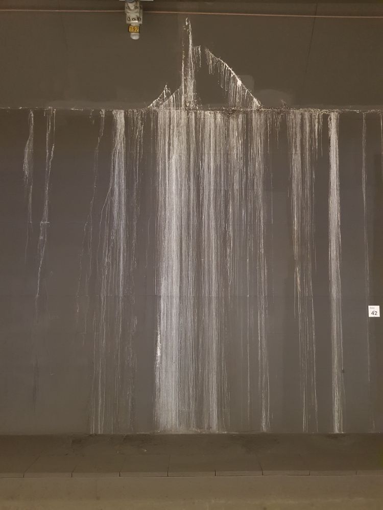 Dunkle Betonwand im Tiefbahnhof mit hellen vertikalen Schlieren, vermutlich von hereingelaufener Flüssigkeit 