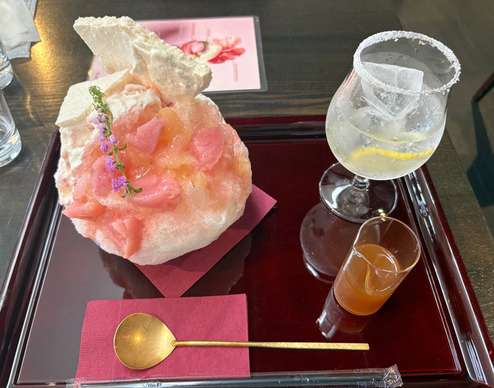 Scrumptious white peach shaved ice and ginger soda are placed on a red lacquer tray with a golden spoon.