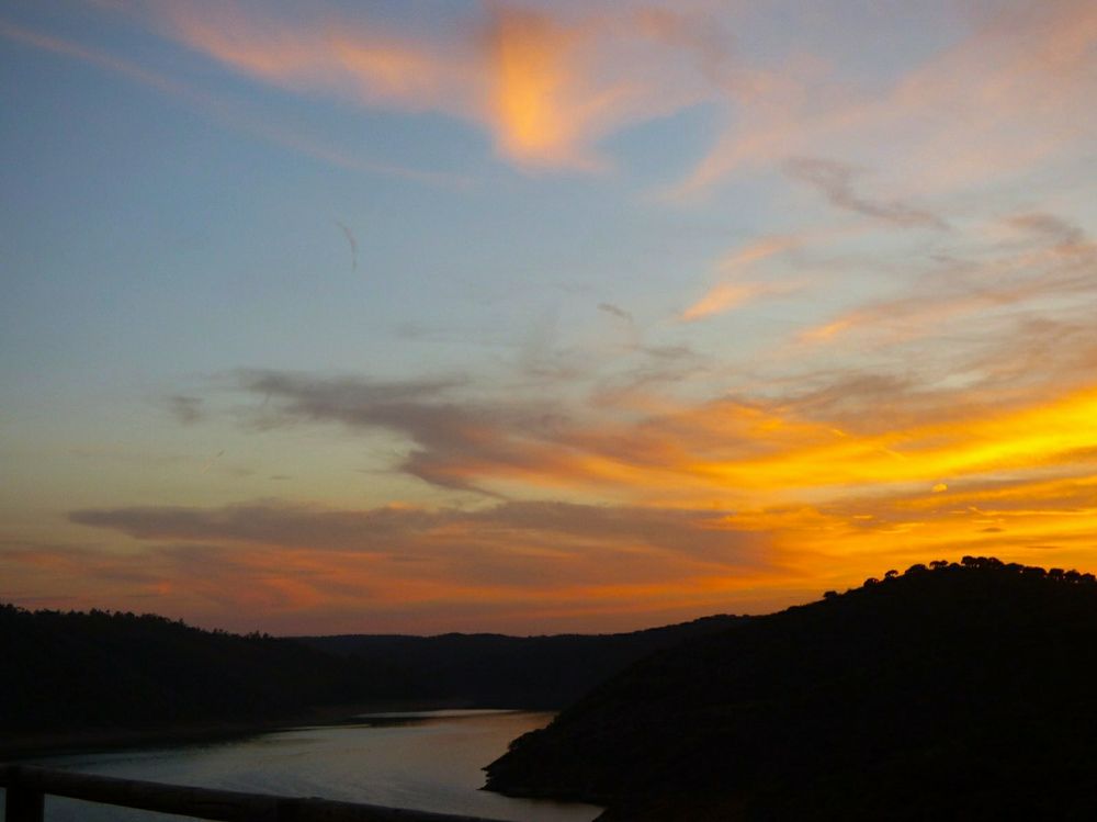 Atardecer en Monfragüe. El cielo es de tonos naranjas brillantes que se reflejan en el Tajo