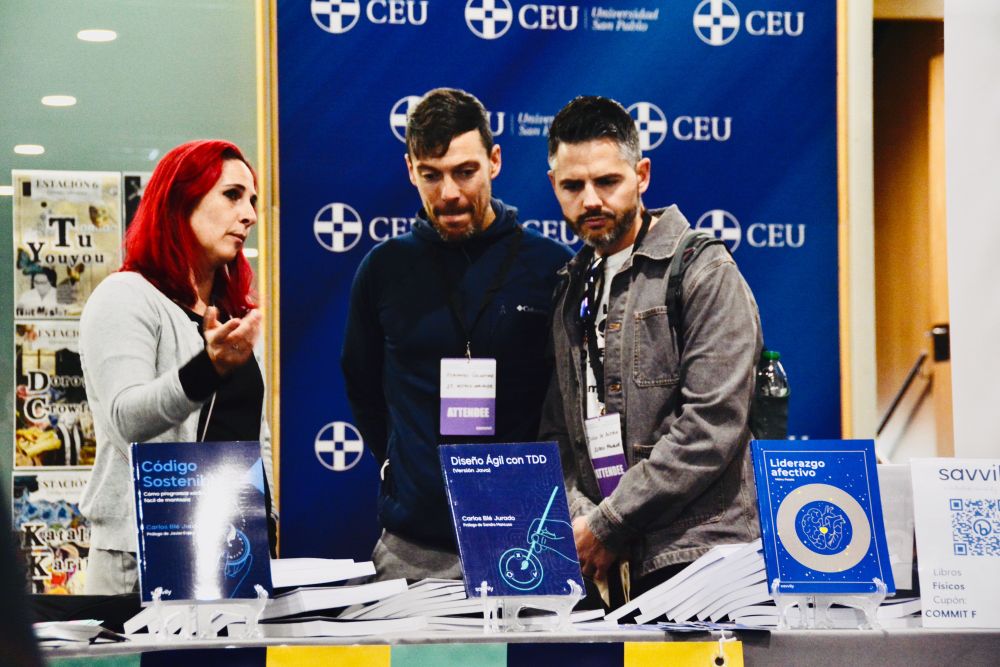 María Blé, directora de la editorial Savvily, habla con dos personas que se han acercado al stand de Lean Mind y Savvily en Commit Conf