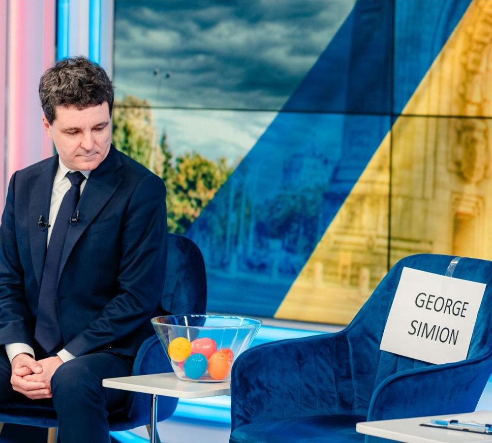 A picture shows a Romanian presidential candidate Nicușor Dan and an empty chair next to him that says 'George Simion'.