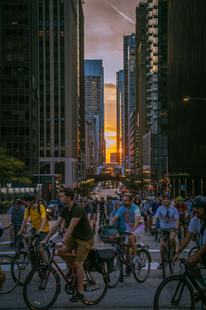 A group of cyclists ride as the sun sets along the Chicago grid system.