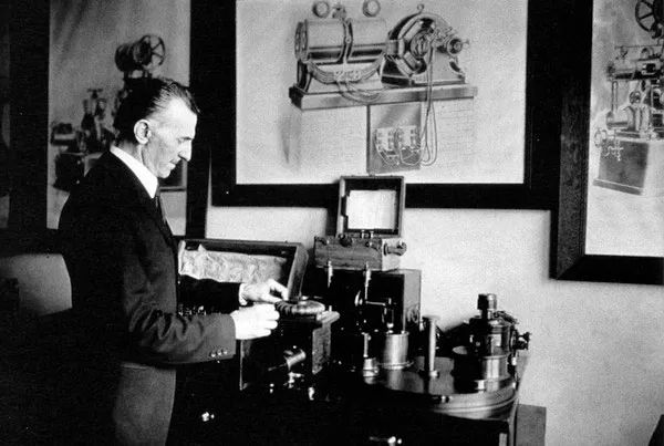 Nikola Tesla Demonstrating Wireless Transmission

In this rare historical photograph, Nikola Tesla is seen in his laboratory, conducting an experiment with wireless transmission technology. Tesla is dressed formally in a dark suit and white-collared shirt, typical of the late 19th and early 20th centuries. His laboratory is filled with scientific instruments, including early electrical generators and Tesla Coil models. Behind him, detailed engineering diagrams of his devices are pinned to the walls, showcasing his meticulous design process.

This image is symbolic of Tesla’s pioneering work in electromagnetism and wireless power transmission, concepts that were revolutionary at the time. Tesla believed that energy could be transmitted wirelessly across great distances, and he spent much of his career trying to prove it. His laboratory was the birthplace of several groundbreaking inventions, including the Tesla Coil, a high-voltage device that could generate massive electrical discharges.

On March 1, 1893, Tesla presented the first public demonstration of radio technology in St. Louis, Missouri, years before Marconi’s patents. In this demonstration, he showcased how radio waves could transmit signals without the need for wires. This concept was a precursor to the development of modern radio, radar, and telecommunications. Unfortunately, due to patent disputes and lack of funding, Tesla’s contributions to radio were largely overshadowed by others.

This image represents a moment in history where Tesla was actively shaping the future of energy and communication. His vision of a world powered wirelessly remained unrealized during his lifetime, but his ideas continue to inspire modern scientific advancements in wireless charging, space-based energy transmission, and more.