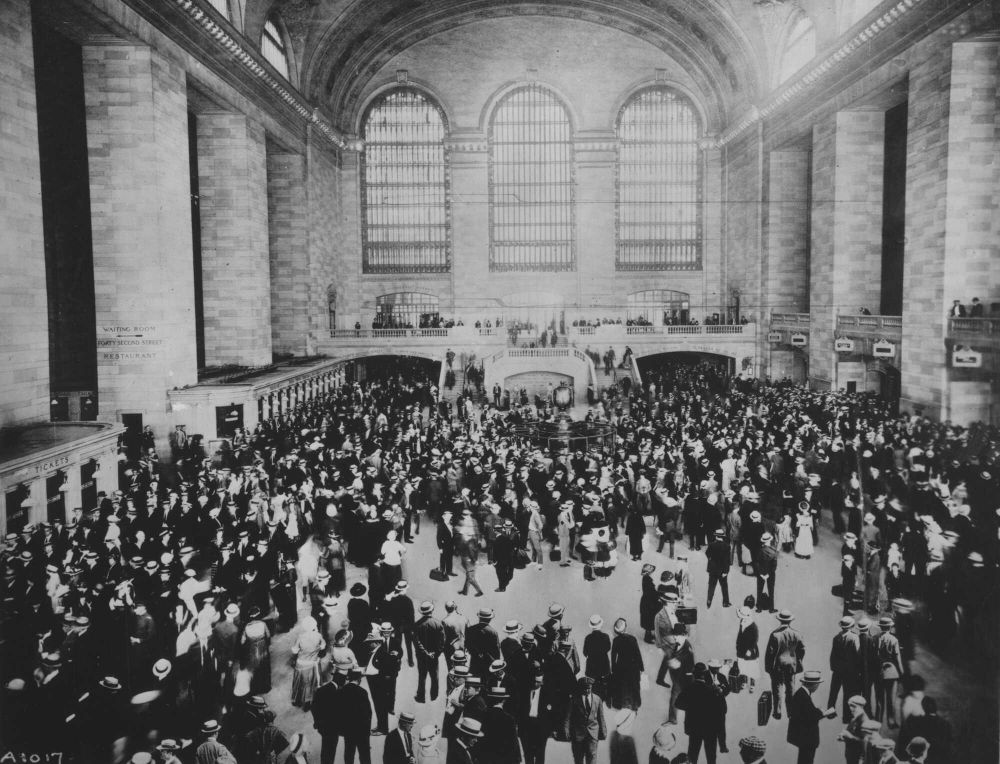The Grand Opening of Grand Central Terminal (1913)

This black-and-white historical photograph captures the bustling main concourse of Grand Central Terminal on its opening day, February 2, 1913. A sea of men and women, dressed in early 20th-century attire, fills the vast hall, highlighting the station’s immediate significance as a transit hub. The grandeur of the terminal’s Beaux-Arts design is on full display, with towering windows flooding the space with natural light, massive stone columns lending an air of classical elegance, and a mezzanine level overlooking the throngs of passengers below. The ticket booths lining the lower walls indicate the high demand for rail travel at the time, as passengers eagerly await their journeys. Designed to handle over 100,000 passengers daily, Grand Central quickly became a symbol of modern transportation and urban sophistication. The station’s opening marked a turning point in New York City’s development, integrating long-distance rail with local transit options. In addition to its function as a transportation hub, Grand Central Terminal was an architectural marvel, with an opulent celestial ceiling in the main concourse featuring constellations in gold leaf against a deep blue background. This image captures a moment in history when New Yorkers and visitors alike marveled at the station’s scale and efficiency. The station’s opening was widely celebrated, solidifying its place as one of the most important railway terminals in the world. Over a century later, Grand Central remains a cultural landmark, connecting millions of people to the heart of Manhattan and preserving its legacy as an icon of early 20th-century infrastructure.