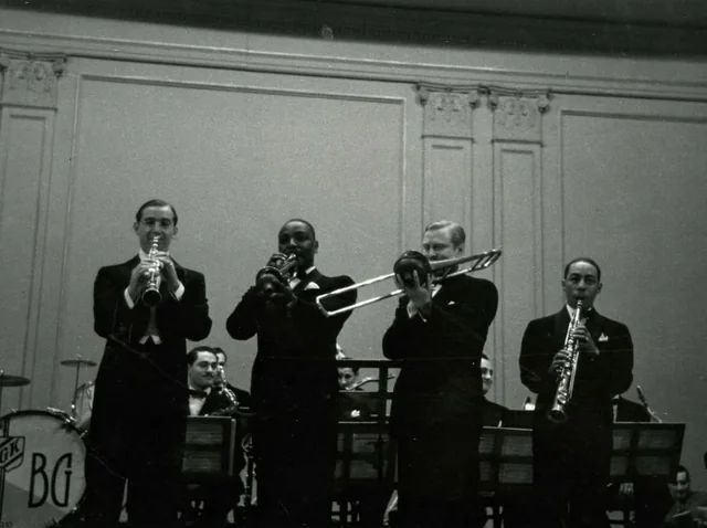 Benny Goodman’s Integrated Band at Carnegie Hall

This powerful image captures the racially integrated lineup of Benny Goodman’s band performing at Carnegie Hall, a bold statement in 1938 America. Featured musicians include Lionel Hampton on vibraphone and Teddy Wilson on piano, both trailblazing Black artists who helped redefine swing music. Goodman’s decision to collaborate with Black musicians in a segregated era was revolutionary, challenging societal norms and paving the way for greater racial integration in music. Their performance at Carnegie Hall was a milestone, blending musical excellence with social progress. The image highlights the intersection of artistry and activism, showing how Goodman and his band used music to bridge divides, proving that talent transcends race in the pursuit of art and innovation.