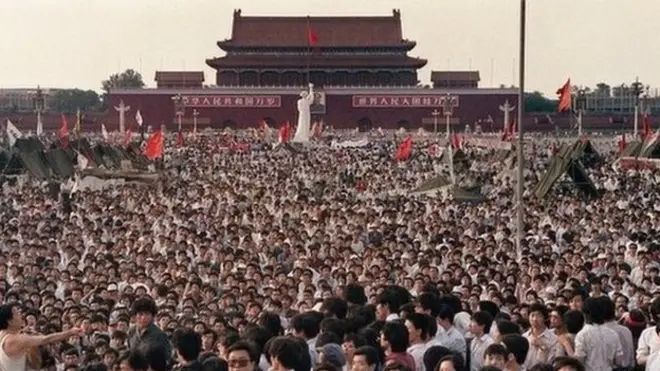 Mass Demonstrations in Tiananmen Square Before the Crackdown

This powerful image shows the immense scale of the student-led protests in Beijing’s Tiananmen Square during the spring of 1989, prior to the military crackdown. Stretching across the vast plaza in front of the Forbidden City, tens of thousands of demonstrators gathered in peaceful assembly, calling for democratic reforms, greater transparency, and an end to government corruption. The focal point of the square is the towering white statue known as the “Goddess of Democracy,” erected by art students as a symbolic counterpart to the nearby portrait of Mao Zedong and a visual embodiment of the movement’s aspirations. Banners and red flags wave above the sea of people, while makeshift tents and loudspeakers signal a temporary, organized encampment. The protests, which began in April 1989 following the death of reformist leader Hu Yaobang, swelled into a massive and sustained sit-in that captured the attention of the global media. The demonstrators came from across Chinese society—students, journalists, intellectuals, and workers—united by a shared desire for political liberalization. While the movement was largely nonviolent, its demands posed a direct challenge to the Chinese Communist Party’s grip on power. For weeks, negotiations between protest leaders and government officials faltered, ultimately culminating in the decision to forcibly clear the square on the night of June 3–4. This image, therefore, preserves a fleeting moment of hope and collective willpower before the violent suppression that followed. It serves as a visual archive of a historic democratic movement and a sobering reminder of its tragic end.