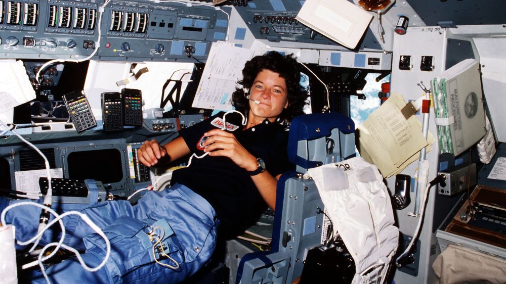 Sally Ride Aboard the Challenger – Inside the Orbiter That Changed History

This photo captures astronaut Dr. Sally Ride mid-mission aboard the Space Shuttle Challenger during STS-7 in June 1983. Ride is pictured floating effortlessly in zero gravity, her hair slightly raised and a headset attached—signs of the weightless environment and her active communication duties. She holds onto a drink pouch and appears relaxed yet focused, fully immersed in the rhythm of life in orbit. Surrounding her are panels filled with switches, wires, data pads, and flight manuals—a complex and controlled chaos that defines the working quarters of a space shuttle mission.

This moment in the cockpit encapsulates the groundbreaking significance of Ride’s presence. As the first American woman in space, her participation aboard Challenger didn’t merely represent a gender milestone; it symbolized the evolving future of spaceflight. Her responsibilities on the mission included operating the shuttle’s robotic arm (Canadarm), which she used to deploy satellites—an extraordinary technical task requiring precision and calm under pressure.

The reflects the human side of space exploration—the adaptability, collaboration, and trust in each crew member’s ability, regardless of gender. It was a quiet rebuttal to years of skepticism about women in space, especially in operational and command roles. Ride’s confident presence amid such a high-tech, high-stakes environment helped reshape the perception of what an astronaut looked like.

More than just a scientific pioneer, Ride became a role model for generations. This image—her body language, professionalism, and seamless integration with her male colleagues—embodies the normalization of diversity in elite scientific spaces. It served as an inspiration not only to aspiring astronauts but also to young scientists, engineers, and dreamers everywhere.

This photo reminds us that space exploration is as much about who we send as it is about where we go.