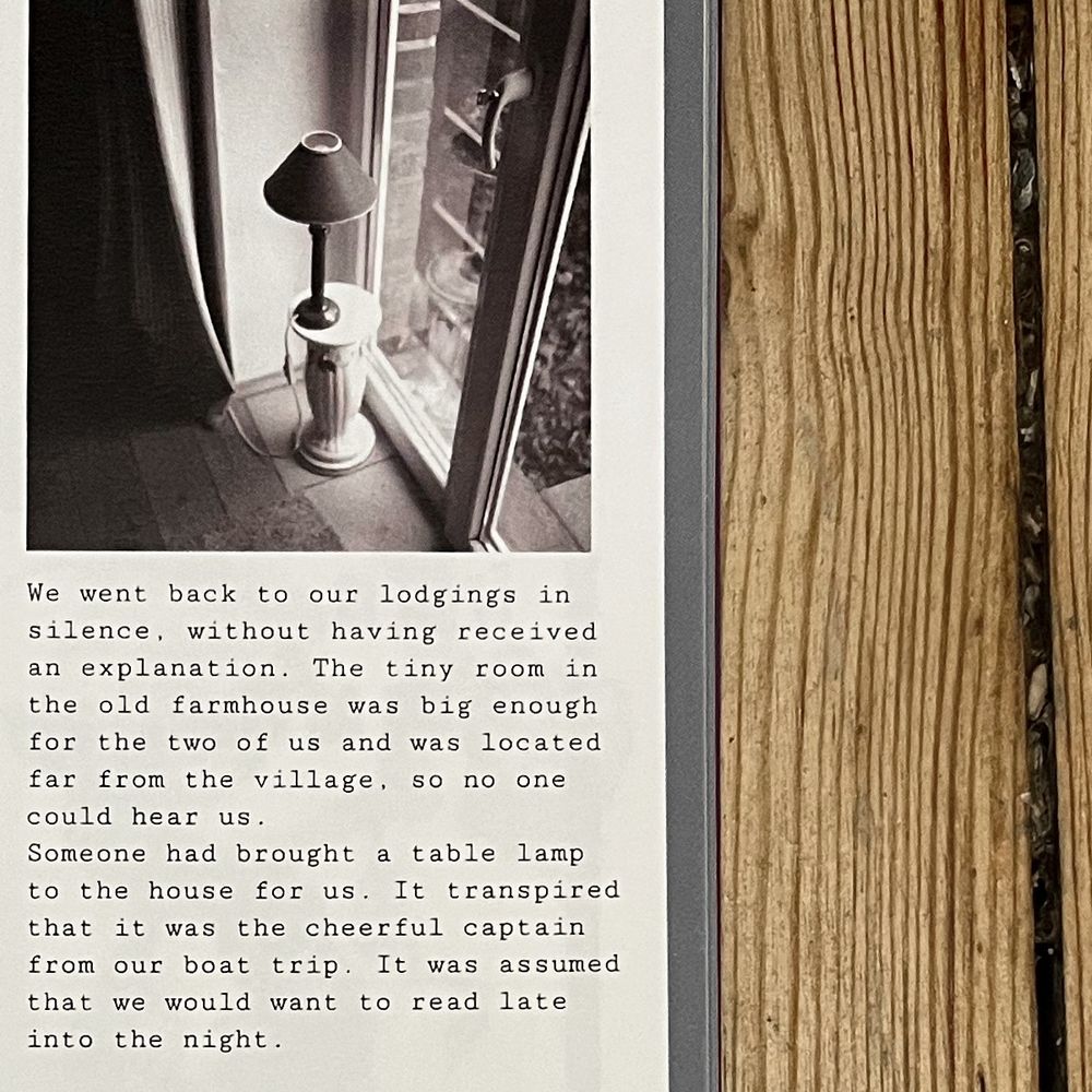 Die Seite aus dem Printmagazin FELD zeigt eine Schwarz-Weiß-Aufnahme von einer Stehlampe auf einem Sockel an einer Glastür. Darunter ein englischsprachiger Text. Rechts im Bild sieh man das Holz des Tisches, auf dem das Magazin liegt.