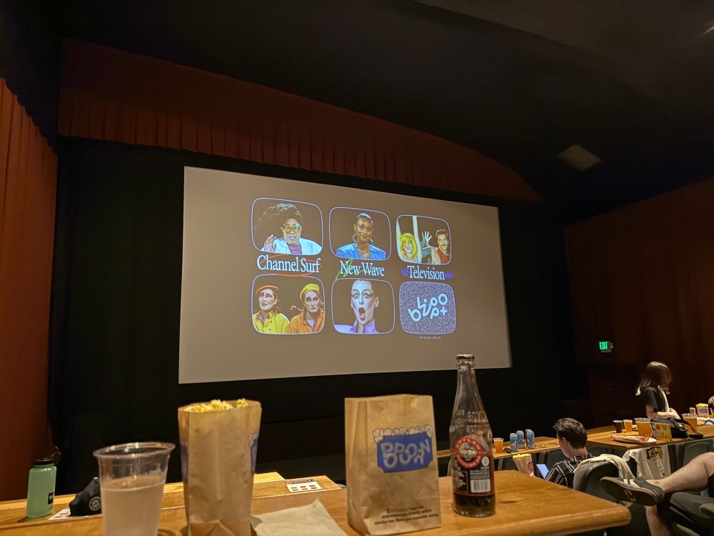 A movie theater screen with an ad for blippo that says “Channel surf, new wave, television” 