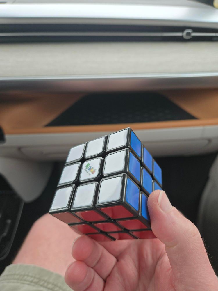 a hand holds a solved rubix cube