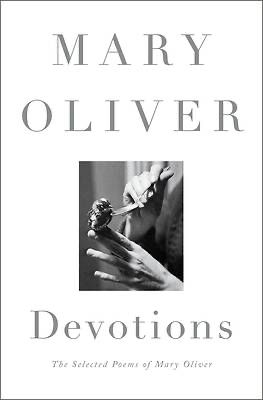 The book cover of Devotions: The Selected Poems of Mary Oliver. The cover has a minimalist white background with the author’s name, “Mary Oliver,” in large, uppercase serif font at the top. Below, there is a black-and-white photograph of a small bird perched on an outstretched hand, while another hand holds a spoon, seemingly offering water to the bird. The title “Devotions” is centered beneath the photograph, followed by the subtitle “The Selected Poems of Mary Oliver” in a smaller font.