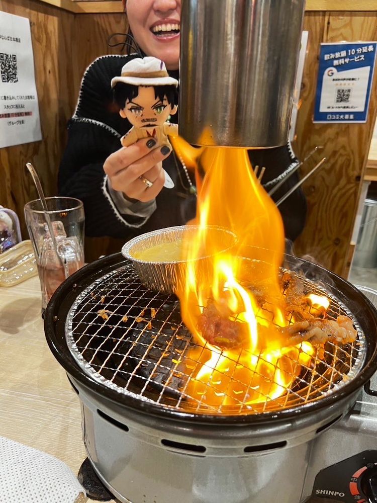 Flames overtake a grill as Rei Hypmic nui looks on from the background. 