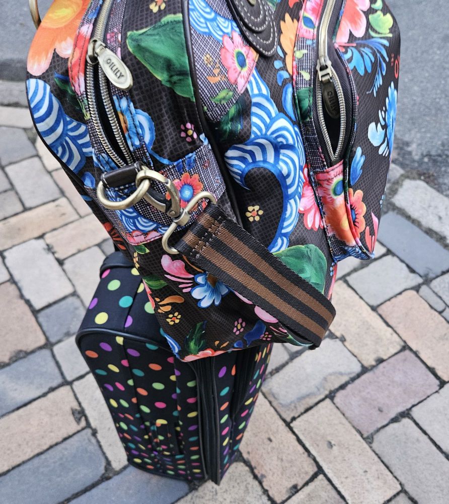 Colorful suitcase with dots and an even more colorful weekender bag with flower print. Setting at the curb and waiting for pickup