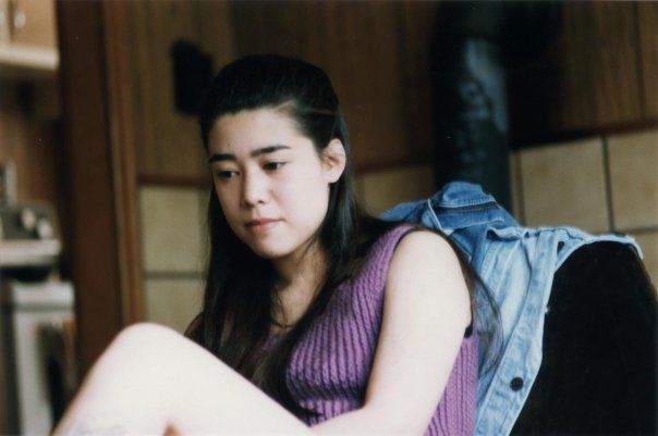 A young women (Sarah DeRoo d. 2020) sitting on a chair in a sleeveless purple top.