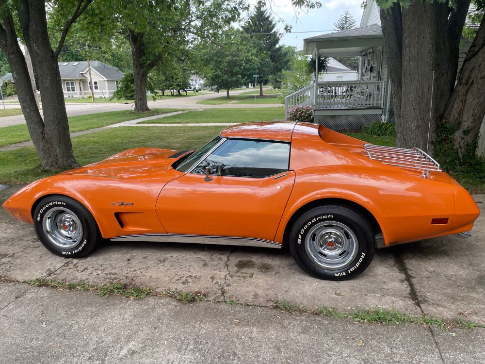 Freshly washed orange 1974 Corvette gleaming in the sun in the driveway.