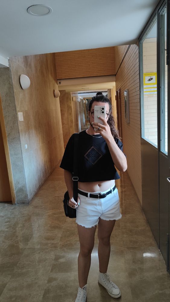 Fotoespejo tapando la cara con el móvil.

Outfit: shorts cortos blancos con cinturón negro, converse altas blancas, camiseta croptop ancha con un rombo de encaje transparente en el pecho