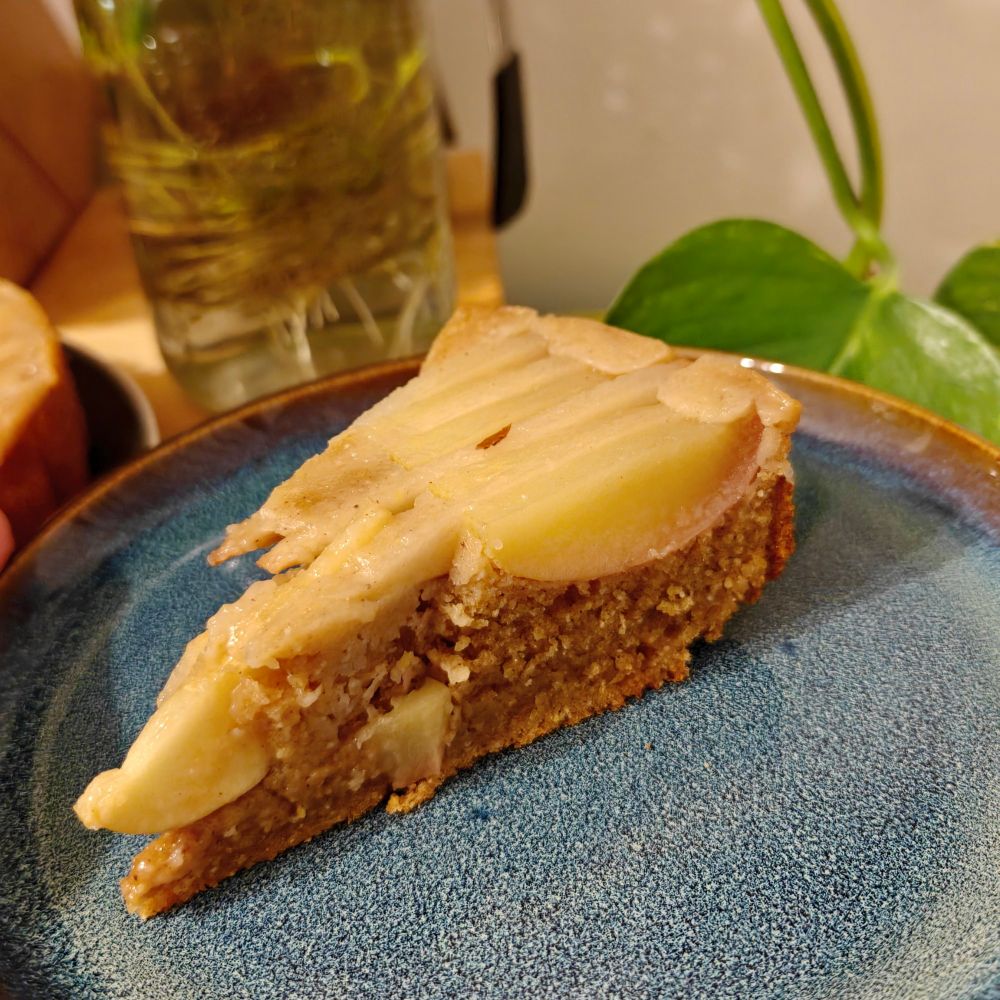 A slice of upside down pear-apple browned butter cornmeal cake on a blue plate. 