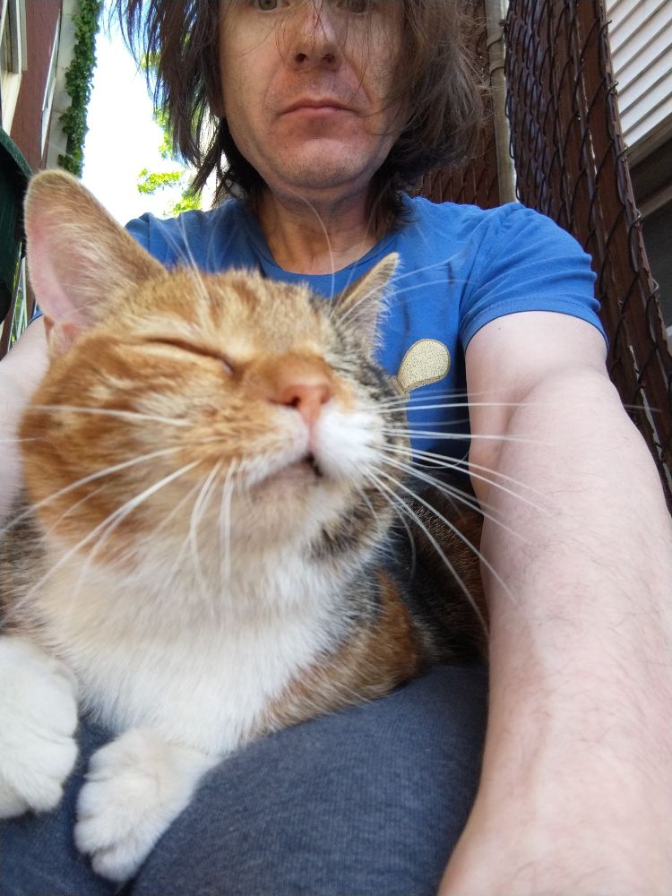 Winky the Pirate Cat on my lap outside our house before we took her in off the street. I needed a haircut. May 2021. 